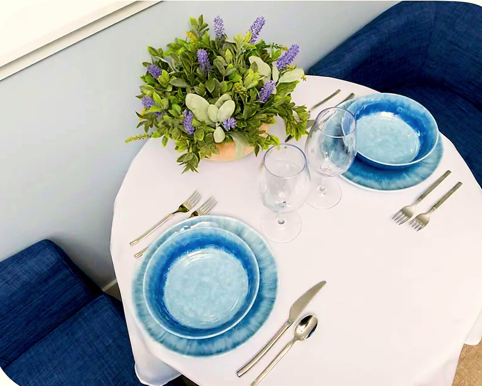 Dining table setting with blue tableware, wine glasses, and floral arrangement